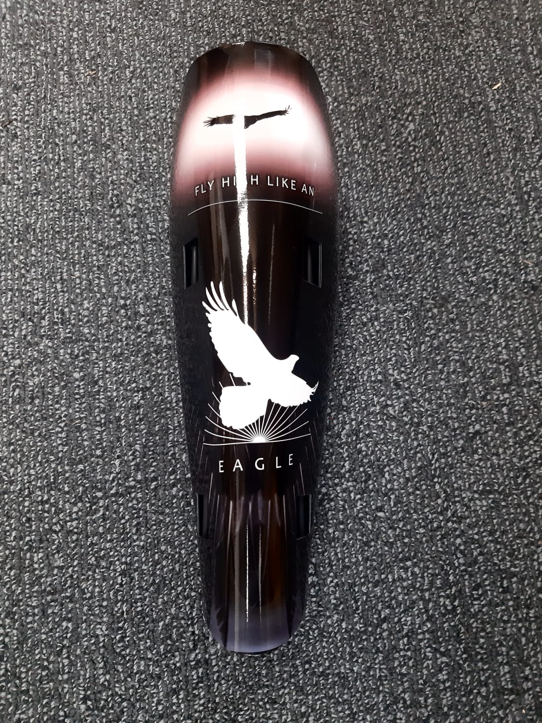 A prosthetic leg cover with white eagle on black background with words Fly Like An Eagle